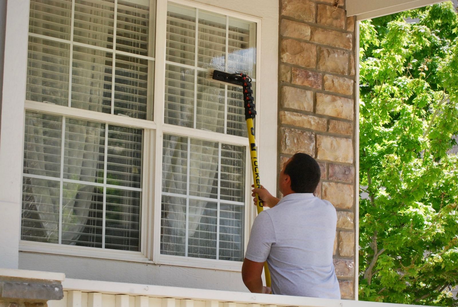 Pure-water pole reaching a second-story window above a brick porch